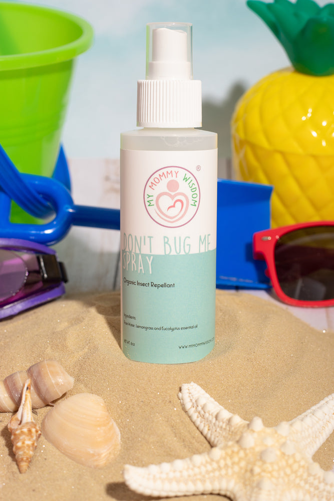 Bottle of My Mommy Wisdom Don’t Bug Me Spray sitting in sand surrounding by beach toys