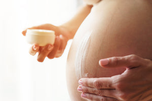 Pregnant woman rubbing My Mommy Wisdom Belly Butter on baby bump to reduce stretch marks