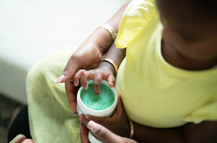 Mom and child dipping finger in My Mommy Wisdom Crown Care Hair Moisturizer