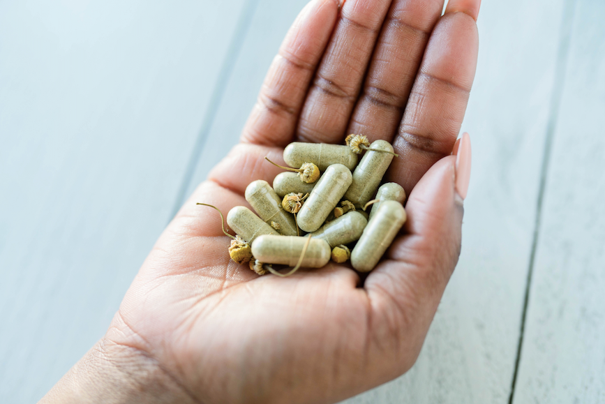 Black woman holding capsules of My Mommy Wisdom Mommy's Milk Booster