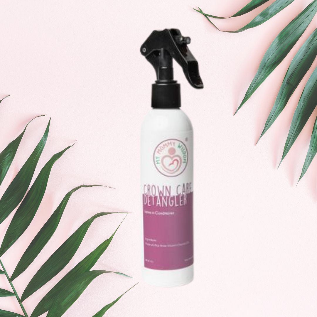 Bottle of My Mommy Wisdom Crown Care Detangler next to green palm tree leaves
