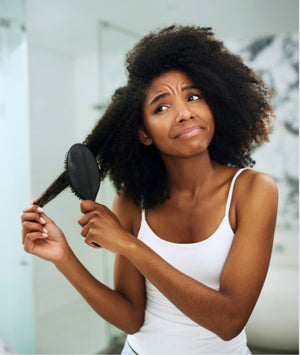 
            
                Load image into Gallery viewer, Black woman wearing a white tank top brushing out thick curly hair
            
        